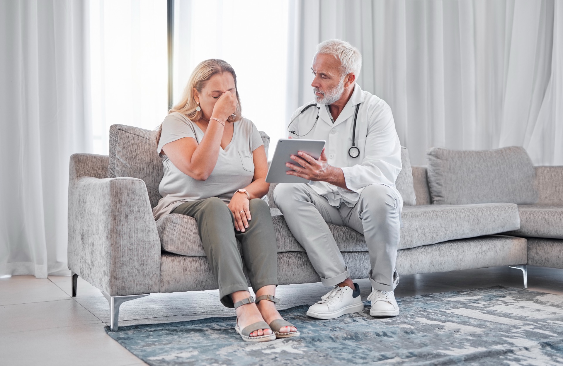 doctor-tablet-bad-news-with-woman-patient-living-room-her-home-with-medicine-professional-healthcare-insurance-cancer-diagnosis-with-female-male-health-consultant_bildgröße ändern